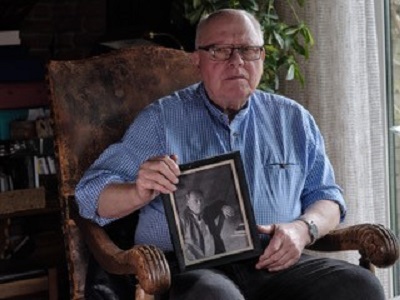 Hans Hermann Briese auf einem Sessel sitzend mit Foto in der Hand